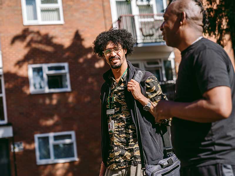 Two people talking outside houses